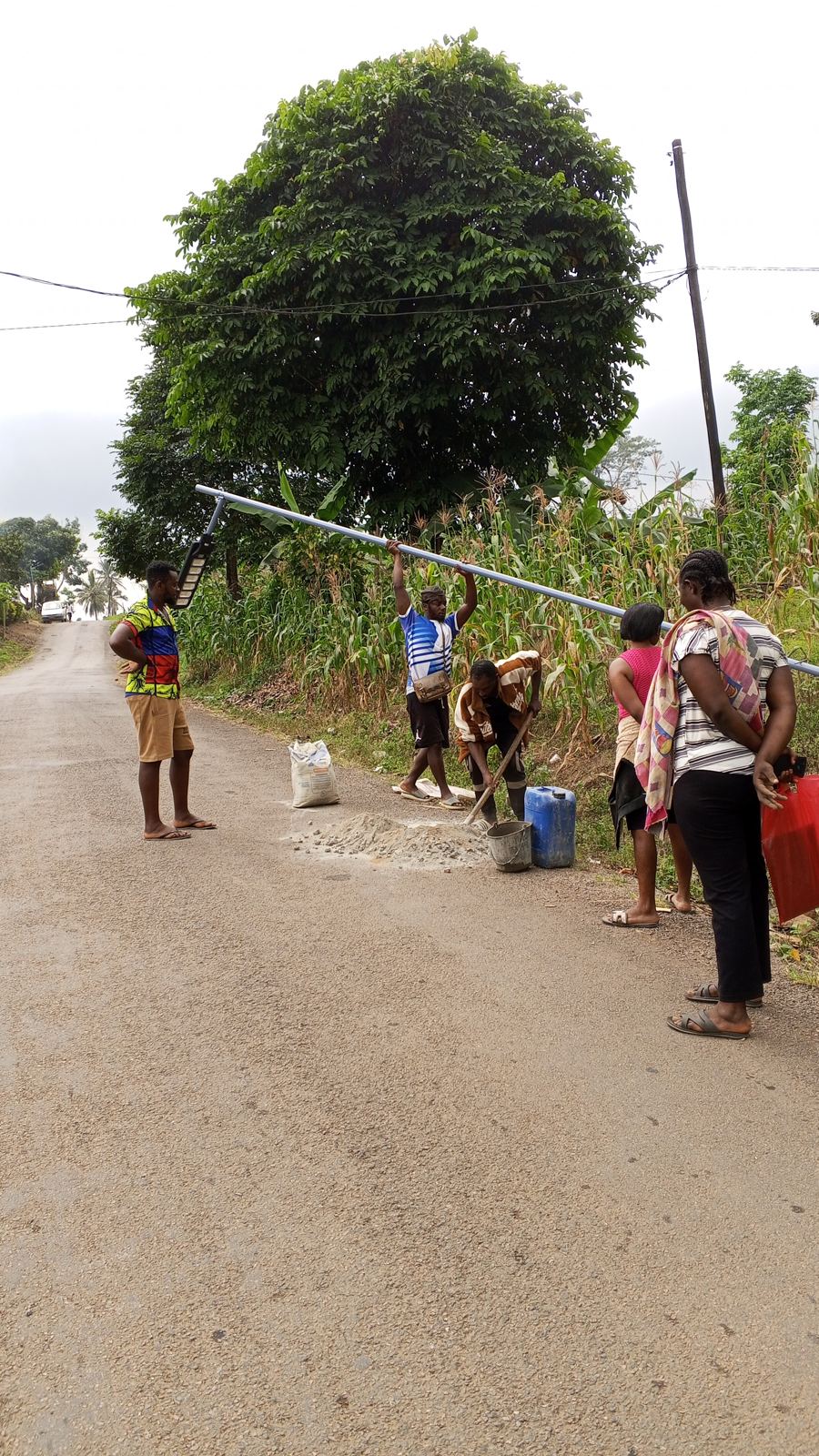 Community members and workers installing a solar lamp pole in Bokova